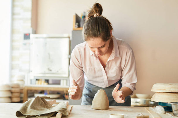 Taille up portret van vrouwelijke Potter shaping Clay tijdens het werken in Studio, kopieer ruimte - Foto, afbeelding