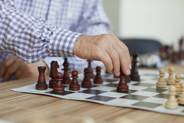 Tanned wrinkled hand of old professional grandmaster making decisive chess move during intense game - Valokuva, kuva