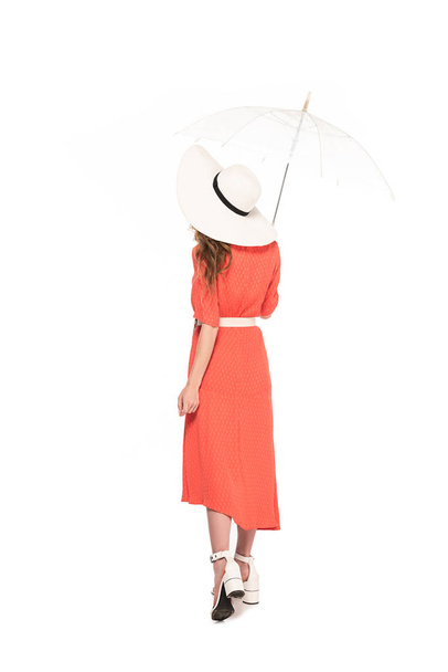 back view of elegant woman in hat and dress holding transparent umbrella isolated on white - Photo, Image