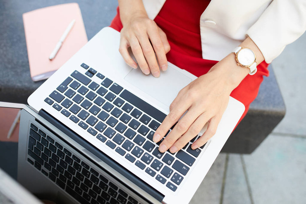 Над просмотром крупным планом неузнаваемая деловая женщина, печатающая на клавиатуре ноутбука во время работы на открытом воздухе, копировальное пространство
 - Фото, изображение
