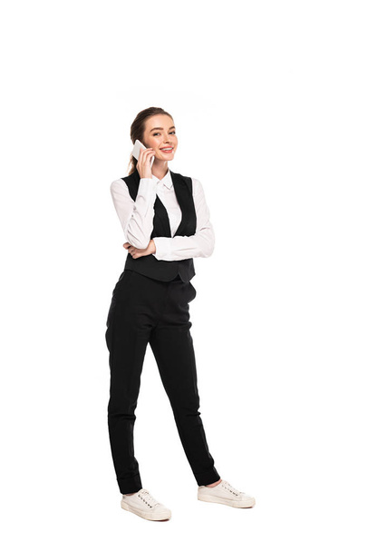 full length view of happy young waitress talking on smartphone isolated on white - Photo, image