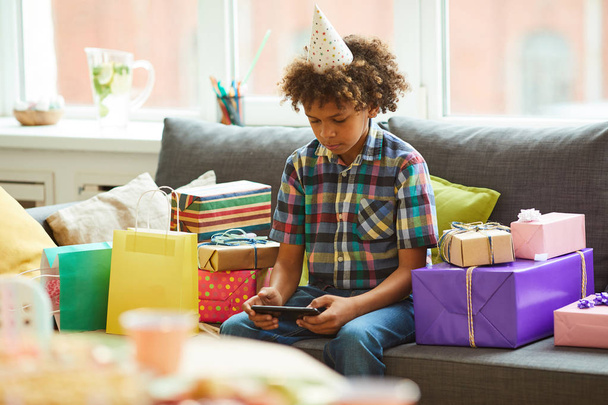 Портрет афро-американського хлопчика з використанням смартфона при відкритті подарунків в день народження, копіювати простір - Фото, зображення