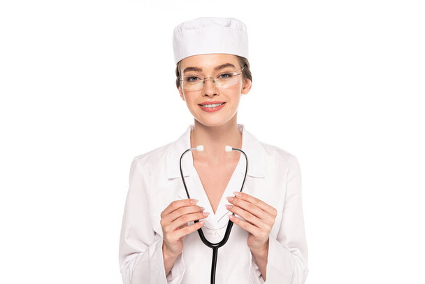 молодой улыбающийся доктор в белом халате, держащий стетоскоп изолированным на белом
 - Фото, изображение