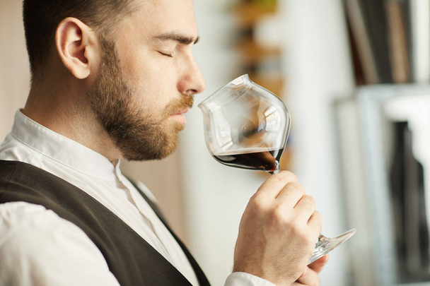Πλευρική θέα του επαγγελματία σόμπμερ κρατώντας γυαλί κρασιού κατά τη διάρκεια της συνεδρίασης γευσιγνωσίας, αντίγραφο χώρου - Φωτογραφία, εικόνα
