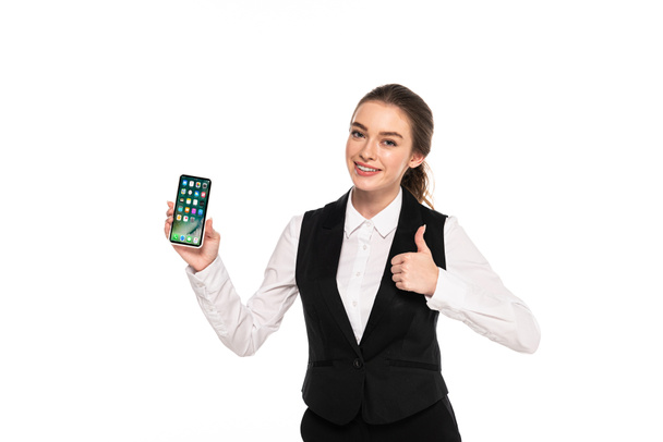 KYIV, UKRAINE - APRIL 7, 2019: happy young waitress holding iPhone and showing thumb up isolated on white - Фото, изображение