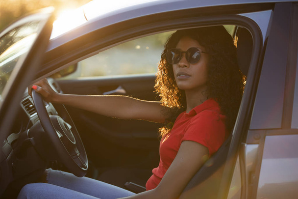Onnellinen nainen kuljettaja istuu autosalongissa auringonlaskun aikaan
 - Valokuva, kuva