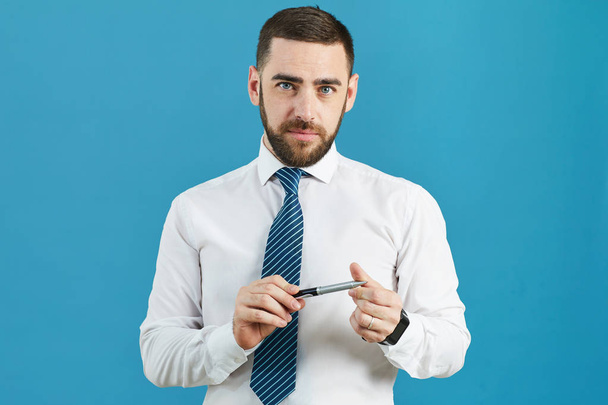 Sisällön muotokuva komea parrakas liikeanalyytikko virallisessa paidassa seisomassa eristettyä taustaa vasten ja kiertämällä kynää ajattelemalla
 - Valokuva, kuva