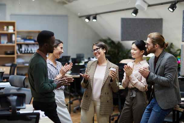 Vista de alto ángulo en el grupo multiétnico de personas de negocios sonriendo alegremente mientras charlan durante el descanso de café en la oficina, espacio para copiar
 - Foto, imagen