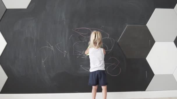 Ein kleines Mädchen wischt Kreide von der Tafel.  - Filmmaterial, Video