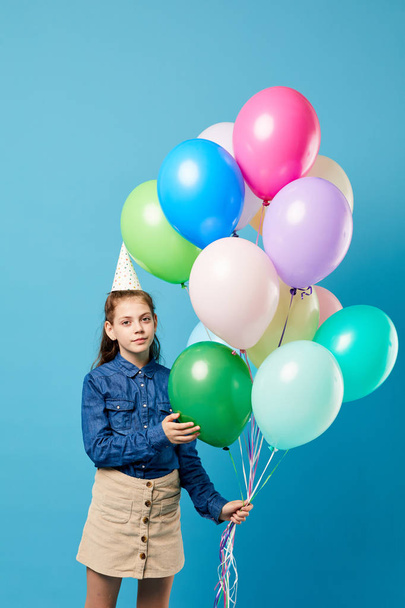 Portrait of teenage girl holding balloons  posing against pastel blue background, Birthday party concept - Фото, изображение