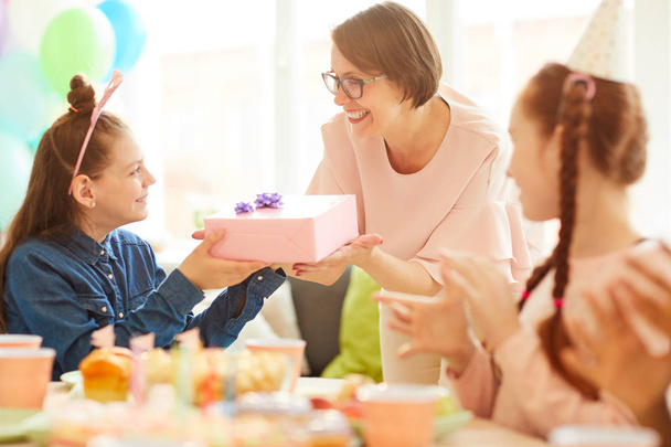 Portrait of happy girl  receiving gift from mom during Birthday party with friends, copy space - Fotoğraf, Görsel