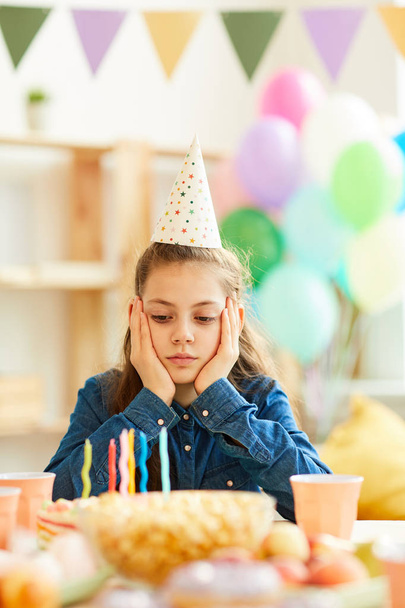Portret smutnej nastoletniej dziewczynki siedzącej samotnie na stole imprezowym na jej urodziny - Zdjęcie, obraz