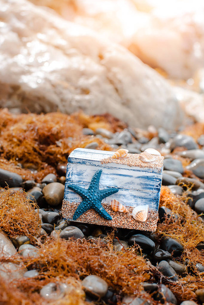 Wooden decorative Chest with sea shells and blue star on the sea coast. - Photo, Image