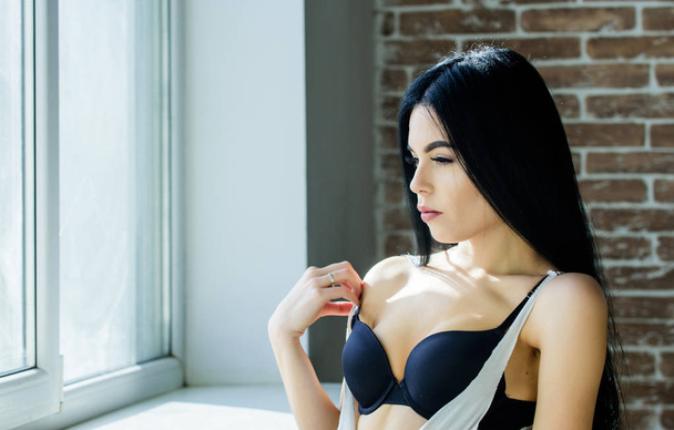 Sexual costume for pleasure. Passionate mysterious lover. Enjoying morning sunlight. Sensual girl sexy breasts relaxing near windowsill. Attractive female sexy lingerie at home. Stunning sexuality - Photo, Image
