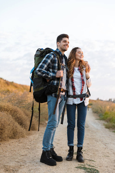 Happy young loving couple outside with backpack in free alternative vacation camping. - 写真・画像
