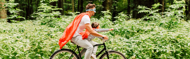 panoramic shot of father and kid riding bicycle while boy looking forward - Photo, Image