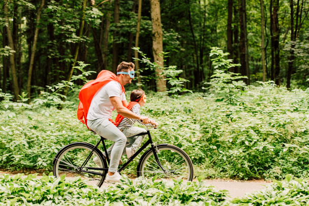 side view of father and son riding bicycle around forest - Foto, afbeelding
