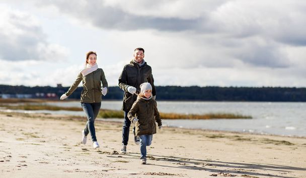 happy family running along autumn beach - Foto, afbeelding