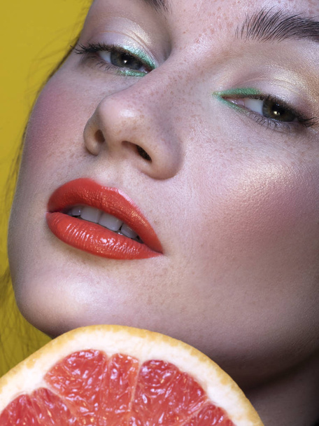 hübsche brünette Frau mit grünem, kreativem Make-up und Grapefruit - Foto, Bild