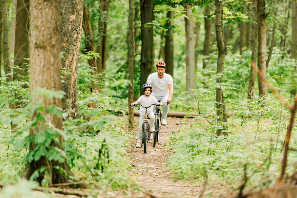 pełny widok długości ojca i syna jazda na ścieżce w lesie - Zdjęcie, obraz
