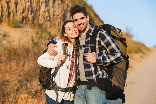 Happy young loving couple outside with backpack in free alternative vacation camping. - Foto, imagen