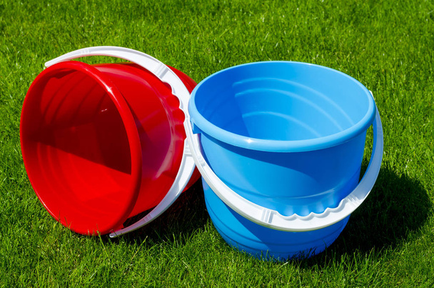 Colored plastic garden buckets on background of green grass - Photo, Image