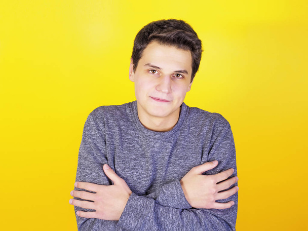 Young man feeling cold against the yellow background - Foto, Imagen