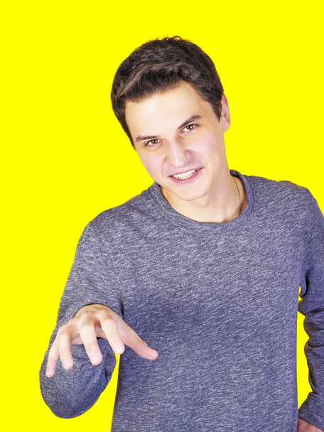 Young man growls on a yellow background - Zdjęcie, obraz