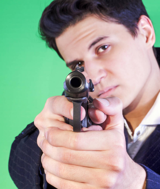 Handsome young man aiming the gun to an invisible target, with selective focus - Fotó, kép