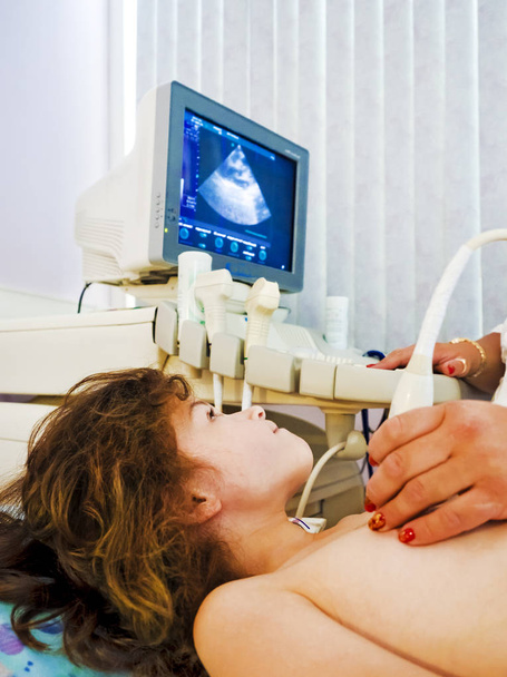 El médico comprueba el corazón del niño acostado en el sofá con una máquina de ultrasonido
 - Foto, imagen
