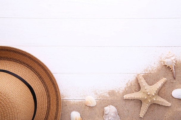Beach hat with seashells on white wooden table - 写真・画像