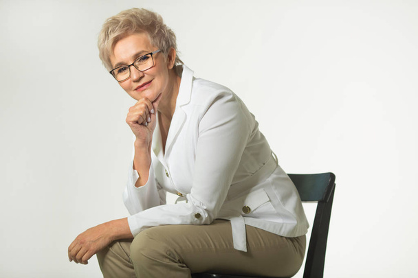 portrait of an adult woman with a short haircut wearing glasses in a white jacket on a white background - Fotoğraf, Görsel