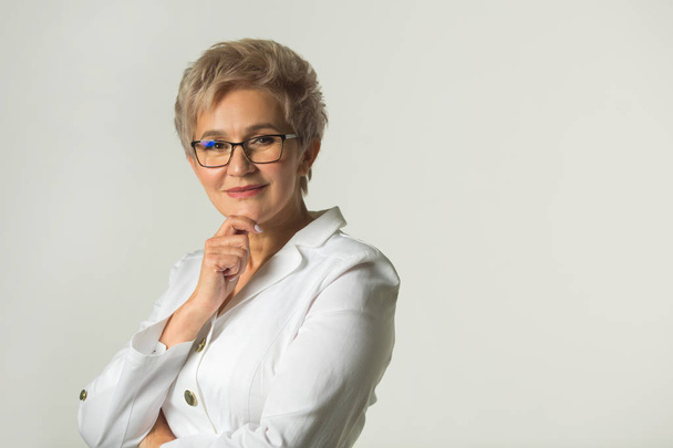 portrait of an adult woman with a short haircut wearing glasses in a white jacket on a white background - Photo, Image