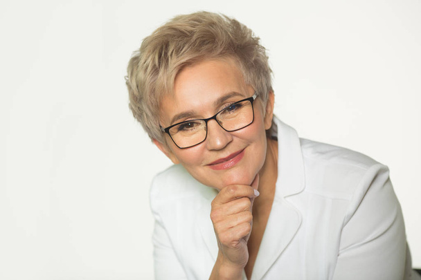 portrait of an adult woman with a short haircut wearing glasses in a white jacket on a white background - Foto, Imagem