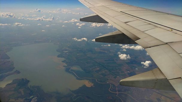 Vliegtuig vleugel uitzicht uit het raam op de bewolkte hemel de aarde - Foto, afbeelding