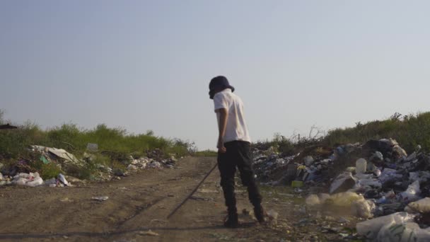 Jongen graaien in vuilnis met stok - Video