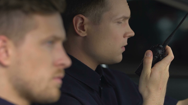 Des policiers en service reçoivent un appel radio bidirectionnel assis dans une voiture de patrouille
 - Séquence, vidéo