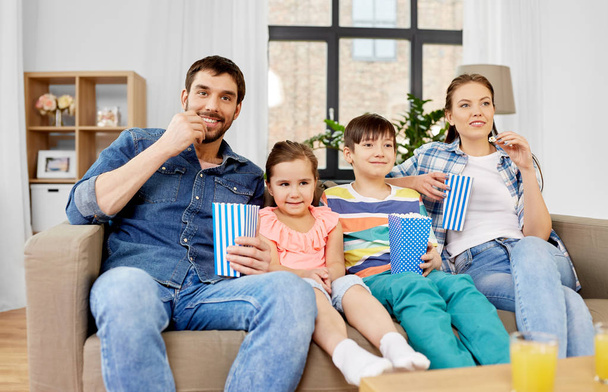 happy family with popcorn watching tv at home - Fotó, kép