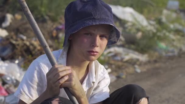 Junge mit schmutzigem Gesicht kauert auf Mülldeponie - Filmmaterial, Video
