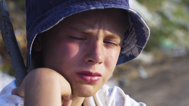 Junge mit schmutzigem Gesicht schaut weit weg in Müllkippe - Filmmaterial, Video