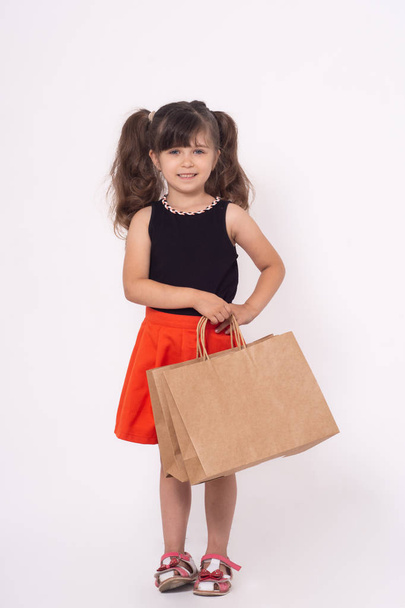 Cute little girl on shopping. Kid with shopping bags. Child in dress goes to shop to buy. - Foto, Imagem