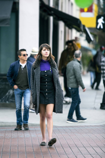 若いかわいい女性ミレニアル世代は、市内を徒歩で歩き、舗装された歩行者の横断歩道を横断します。彼女は通勤者か観光客で、探検や観光をしている.  - 写真・画像