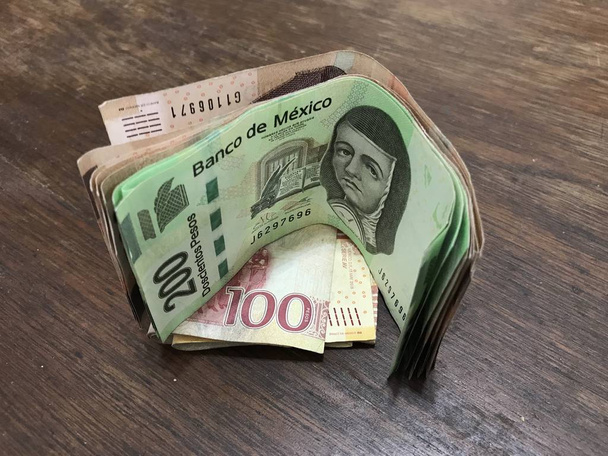 Mnoho smíšených mexických Peso se rozprostřel na dřevěném stole - Fotografie, Obrázek