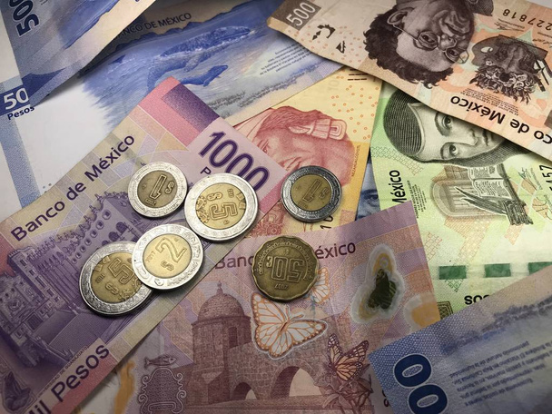 Muchos billetes mixtos de peso mexicano repartidos sobre un escritorio de madera
 - Foto, imagen