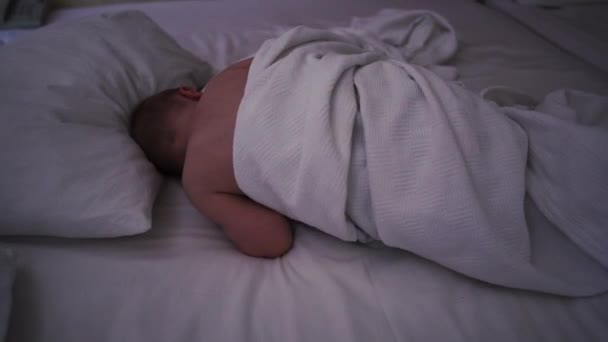 Slapende naakte baby ligt op het grote bed in de hotelkamer in slow motion - Video
