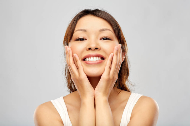 happy smiling young asian woman touching her face - Foto, Imagem