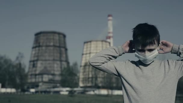 Mladý chlapec položil masku proti znečištění do komína továrny a podíval se na kameru. Koncepce znečišťování ovzduší - Záběry, video