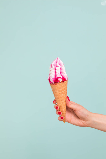 Female hand holding ice cream in waffle cone - Foto, afbeelding
