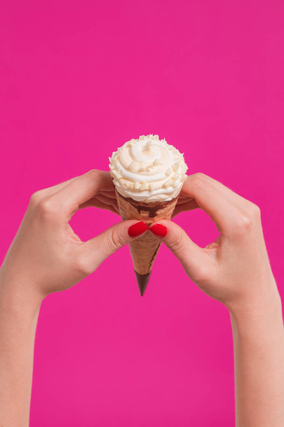 Female hand holding ice cream in waffle cone - Foto, imagen