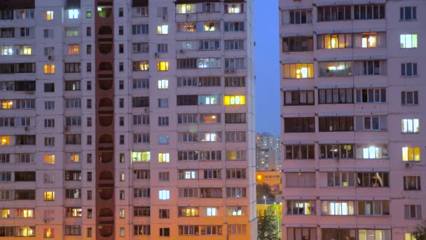 Νυχτερινή λήξη των φωτισμένου παραθύρων του κτιρίου τη νύχτα με άτομα που ζουν σε διαμερίσματα με μπαλκόνι. Έννοια της κατανάλωσης ηλεκτρισμού. Δείτε από κάτω. Οδός της πόλης το βράδυ - Πλάνα, βίντεο